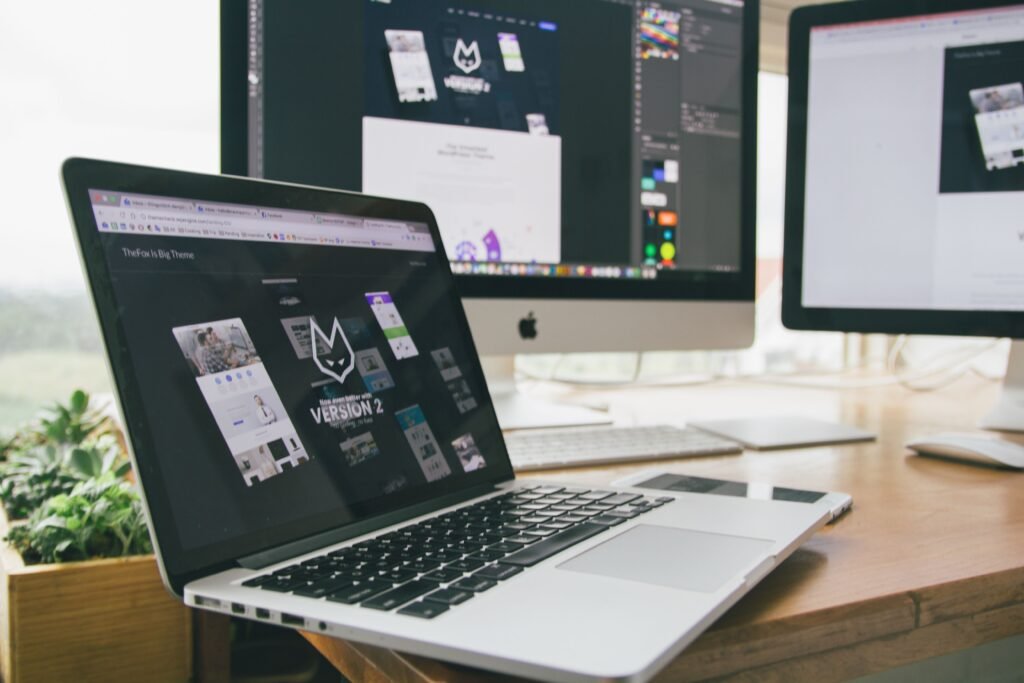 Laptop and external monitors displaying website design and page layout work