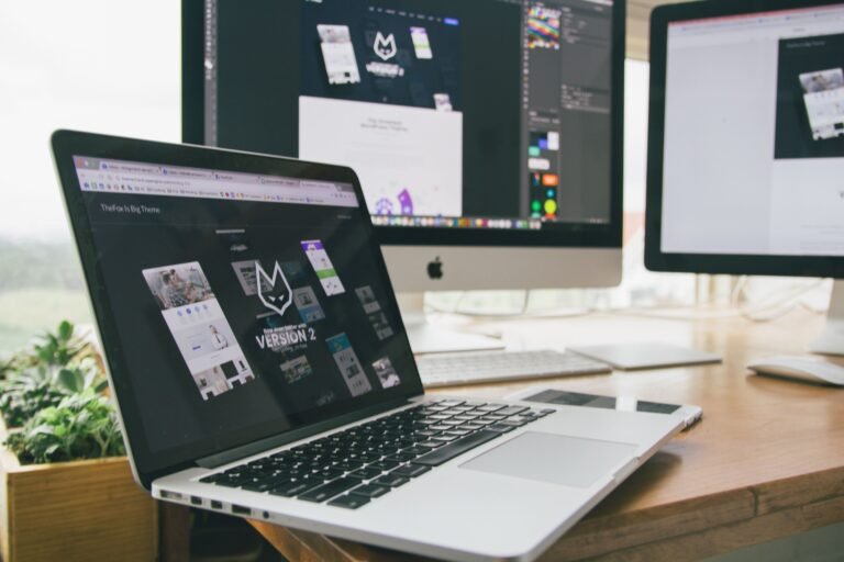 Laptop and external monitors displaying website design and page layout work