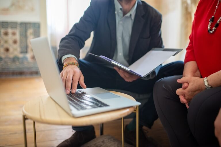Consultant reviewing documents and a laptop with a client during a meeting